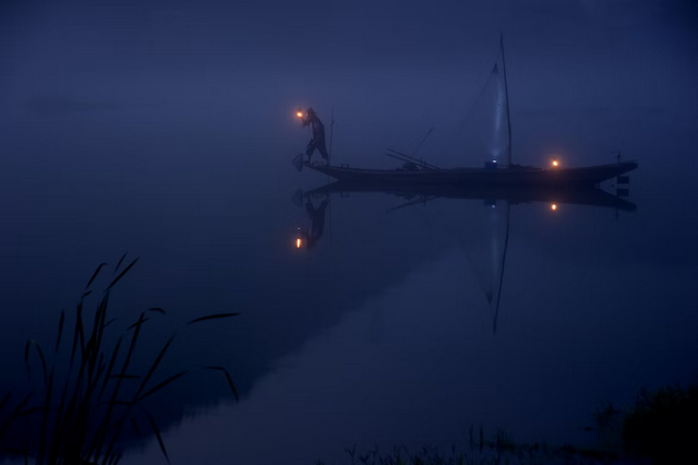 рыболов с фонарем на лодке