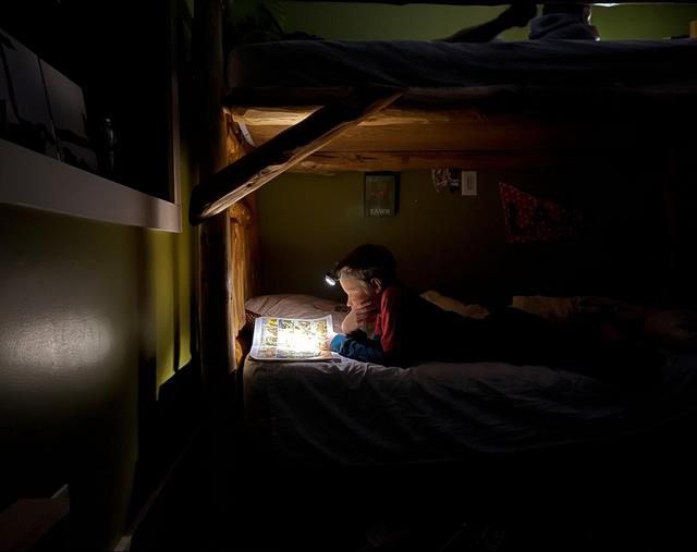 дитина читає з налобним ліхтариком